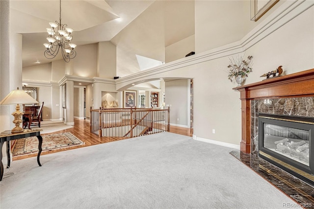 carpeted living room featuring high vaulted ceiling, a chandelier, and a high end fireplace