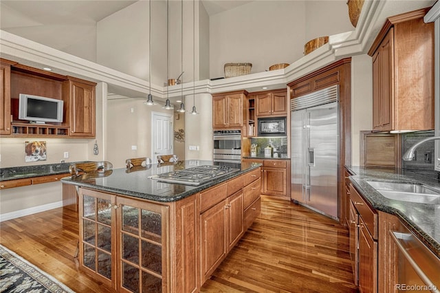 kitchen with hardwood / wood-style flooring, built in appliances, high vaulted ceiling, and a kitchen island