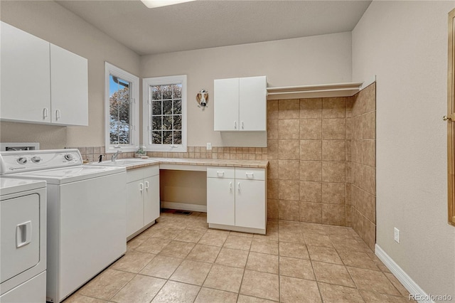 laundry room with cabinets, sink, a textured ceiling, light tile patterned floors, and washing machine and dryer