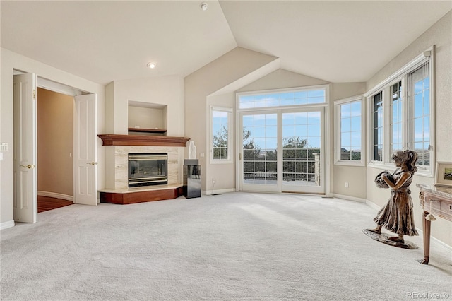 unfurnished living room featuring a high end fireplace, carpet flooring, and lofted ceiling