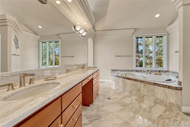 bathroom with a wealth of natural light, vanity, lofted ceiling, and tiled bath