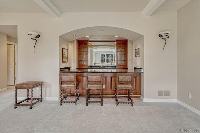 bar with beamed ceiling and light colored carpet