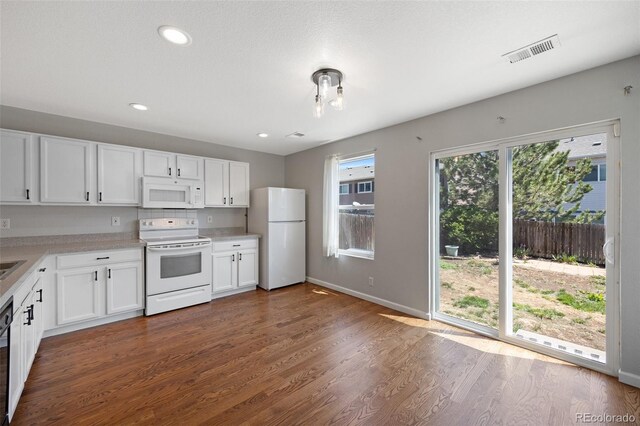 11050 Gaylord St, Northglenn, CO 80233 - kitchen with white appliances, white cabinetry, light countertops, dark wood-style flooring, and baseboards