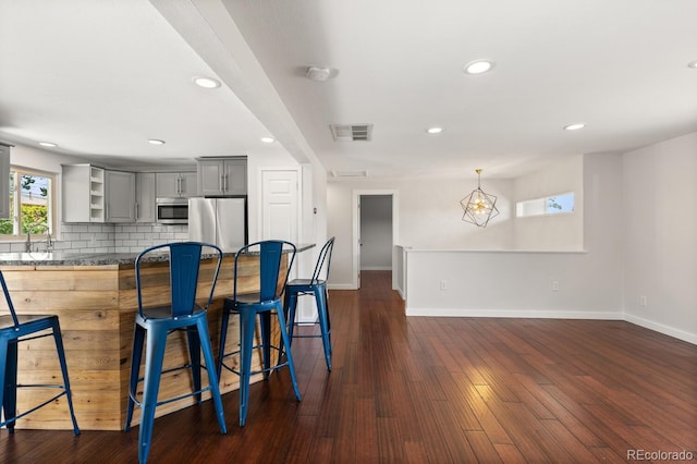 4381 Dixon Dr, Westminster, CO 80031 - kitchen with appliances with stainless steel finishes, open shelves, gray cabinetry, a kitchen breakfast bar, and baseboards