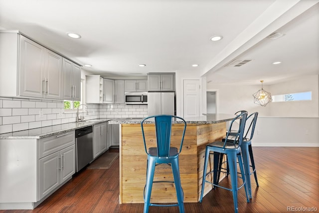 4381 Dixon Dr, Westminster, CO 80031 - kitchen featuring stainless steel appliances, tasteful backsplash, a sink, a kitchen island, and a kitchen breakfast bar