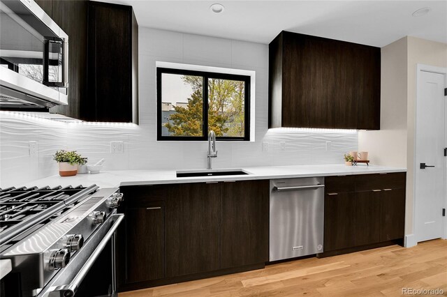 2162 S Ash St, Denver, CO 80222 - kitchen featuring appliances with stainless steel finishes, a sink, tasteful backsplash, and light countertops