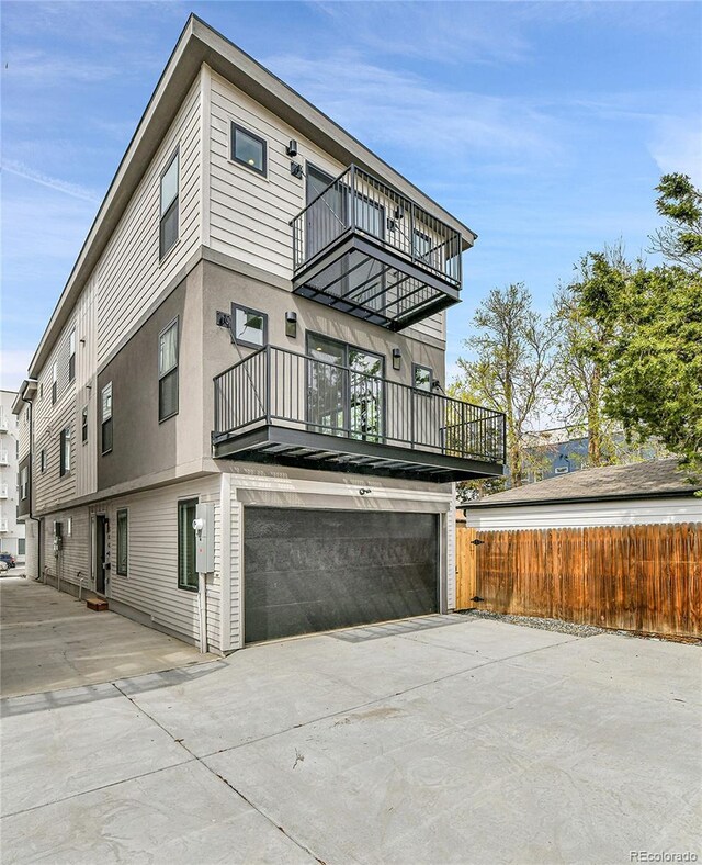 2162 S Ash St, Denver, CO 80222 - view of front facade with a balcony, fence, an attached garage, and concrete driveway