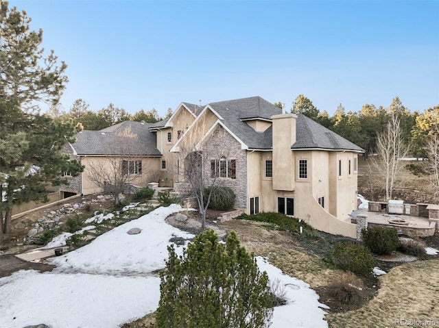 view of front facade featuring an outdoor fire pit, stone siding, a patio area, and stucco siding