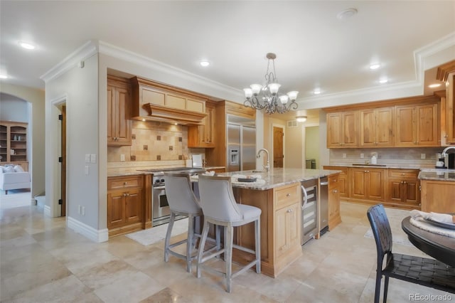 kitchen featuring light stone counters, a breakfast bar area, custom range hood, a kitchen island with sink, and high quality appliances