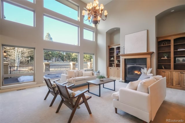 living area featuring a glass covered fireplace, light carpet, a notable chandelier, and visible vents