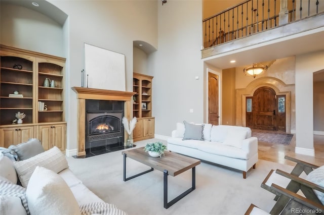 living room featuring a tile fireplace, baseboards, and a high ceiling