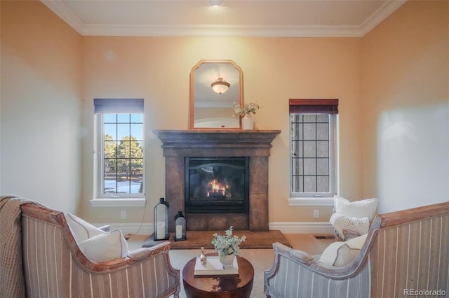 living area with baseboards, a glass covered fireplace, visible vents, and crown molding