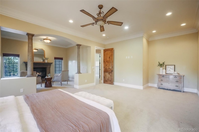 bedroom with light carpet, a warm lit fireplace, decorative columns, and baseboards