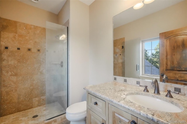 bathroom with tiled shower, vanity, and toilet