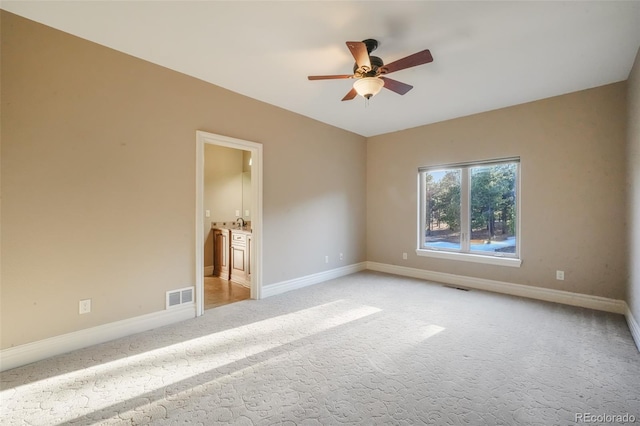 empty room featuring a ceiling fan, visible vents, light carpet, and baseboards