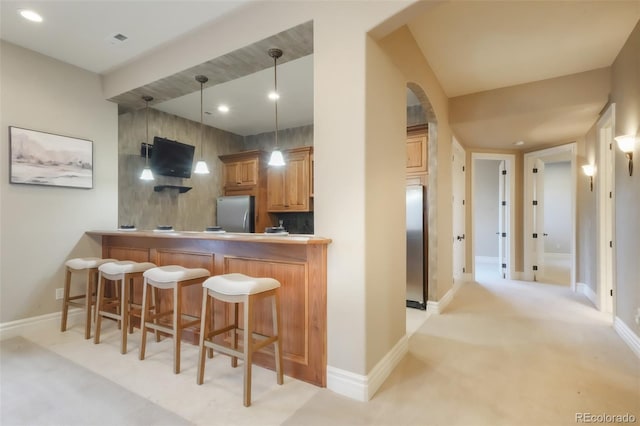 kitchen with freestanding refrigerator, baseboards, and a breakfast bar area