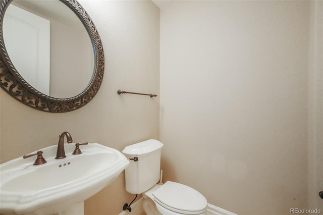 half bathroom with a sink, toilet, and baseboards