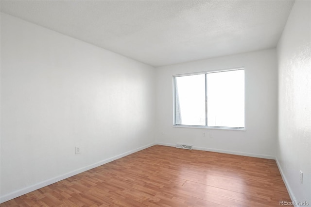 empty room featuring a textured ceiling and light hardwood / wood-style floors