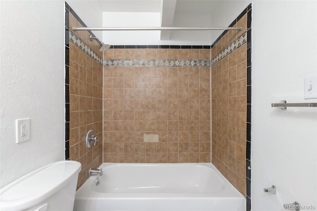 bathroom with tiled shower / bath combo and toilet