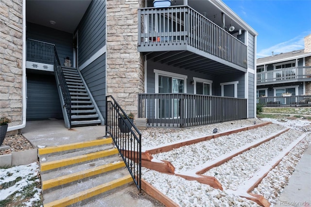 snow covered property entrance featuring a balcony