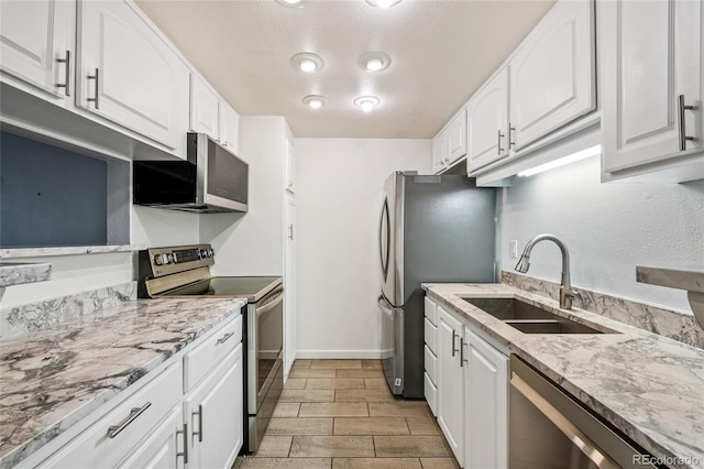 kitchen featuring light stone countertops, stainless steel appliances, sink, light hardwood / wood-style floors, and white cabinetry