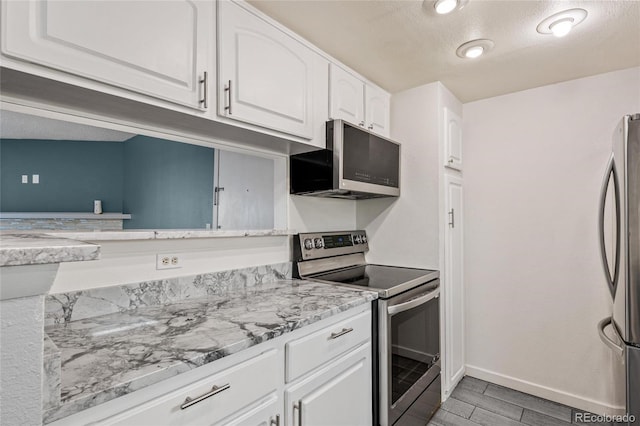 kitchen featuring light stone countertops, a textured ceiling, light hardwood / wood-style floors, white cabinetry, and stainless steel appliances