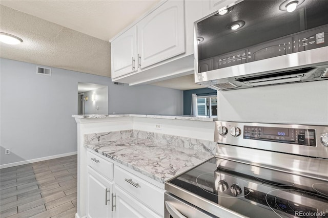 kitchen featuring appliances with stainless steel finishes, light wood-type flooring, a textured ceiling, and white cabinetry