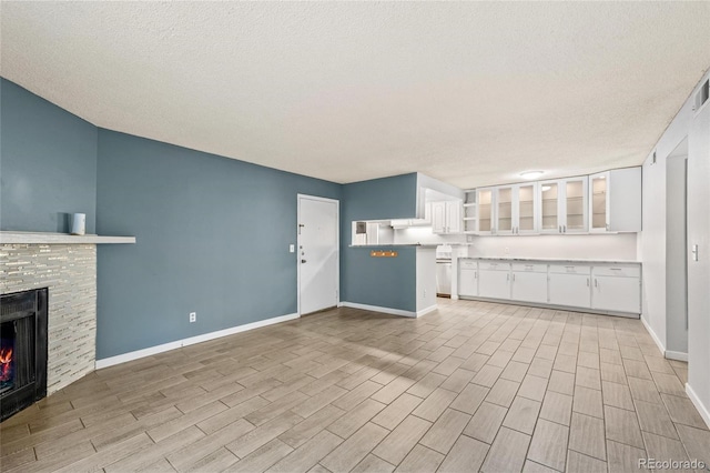 unfurnished living room featuring a fireplace, a textured ceiling, and light hardwood / wood-style floors