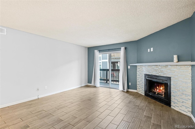 unfurnished living room featuring a fireplace, light hardwood / wood-style floors, and a textured ceiling