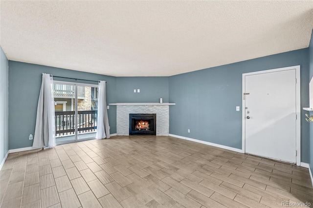 unfurnished living room featuring a stone fireplace, light hardwood / wood-style floors, and a textured ceiling