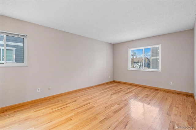 unfurnished room with light hardwood / wood-style flooring and a textured ceiling