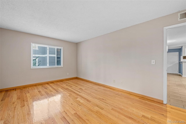 spare room with a textured ceiling and light wood-type flooring