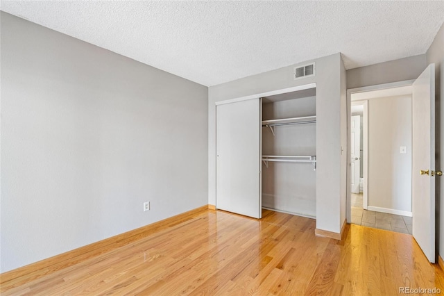 unfurnished bedroom featuring a closet, hardwood / wood-style floors, and a textured ceiling