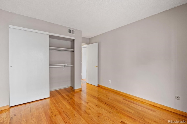 unfurnished bedroom with a closet, a textured ceiling, and light hardwood / wood-style flooring