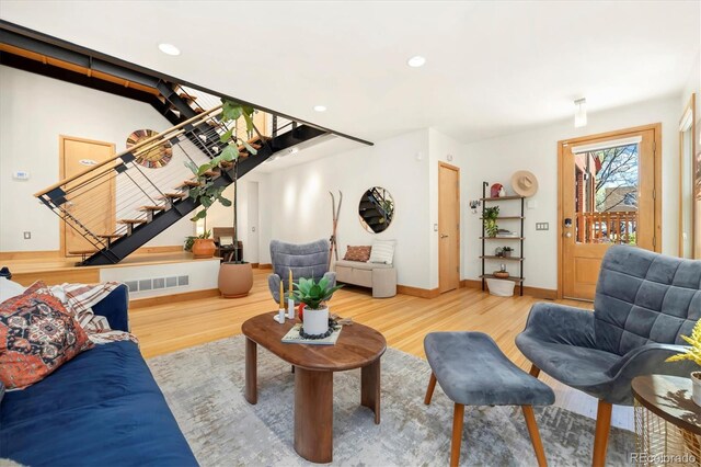 living room with visible vents, baseboards, recessed lighting, wood finished floors, and stairs