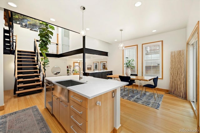 kitchen with recessed lighting, a sink, a center island with sink, and light wood-type flooring
