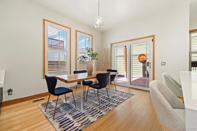 dining room with light wood finished floors, baseboards, and visible vents