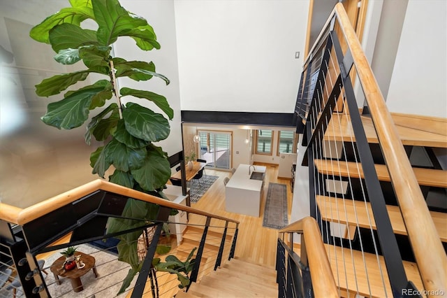 staircase with wood finished floors and a towering ceiling