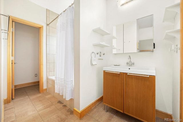 bathroom with baseboards, shower / bath combo with shower curtain, and vanity