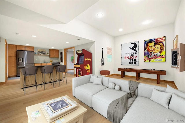 living area featuring recessed lighting, wet bar, light wood-style flooring, and baseboards