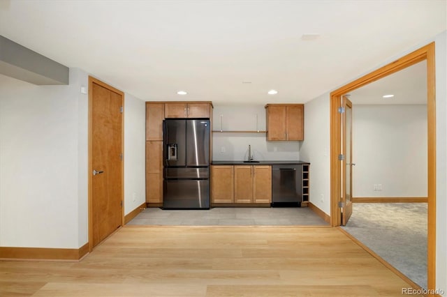 kitchen with light wood-style flooring, dishwashing machine, stainless steel refrigerator with ice dispenser, and a sink