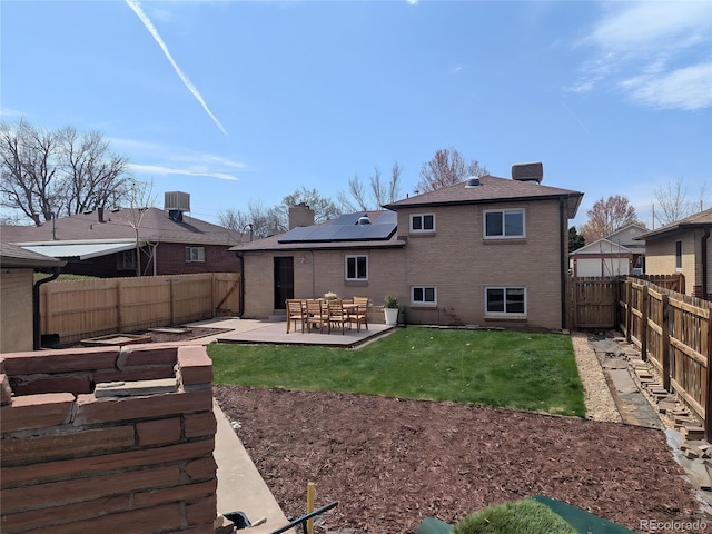 back of property with roof mounted solar panels, a fenced backyard, brick siding, and central AC unit