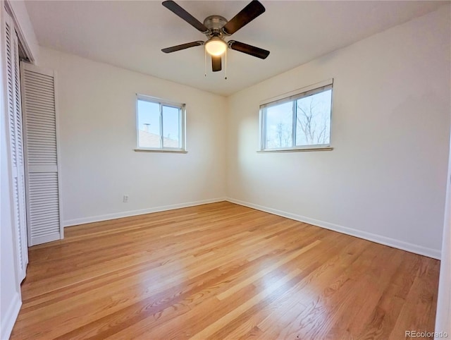 unfurnished bedroom featuring baseboards, light wood-style floors, a closet, and multiple windows