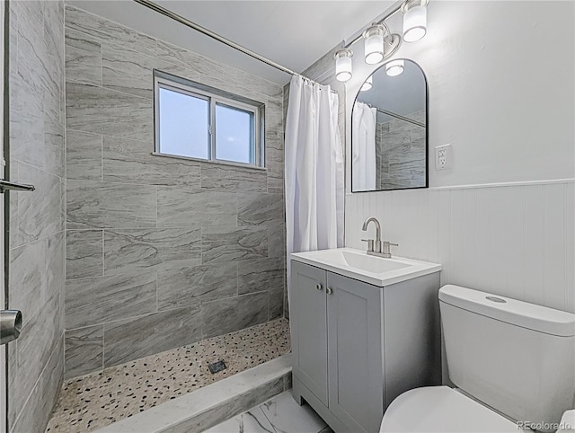 full bath with marble finish floor, a tile shower, toilet, and vanity