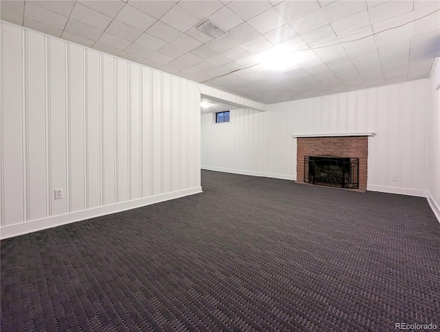 basement with dark carpet, baseboards, visible vents, and a fireplace
