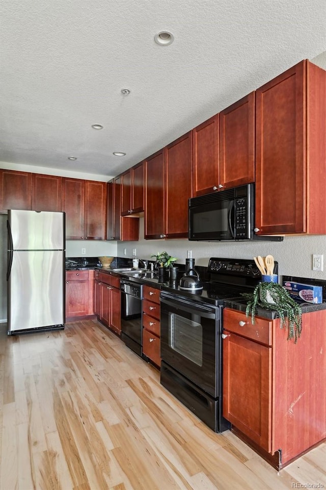 3195 Blake St Unit 106, Denver, CO 80205 - kitchen featuring black appliances, light wood-type flooring, dark countertops, reddish brown cabinets, and a textured ceiling