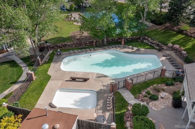 community pool with a lawn, a patio area, and a fenced backyard