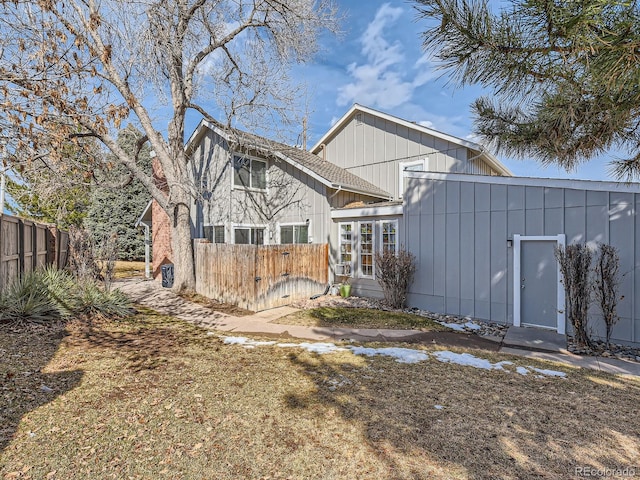 rear view of house featuring board and batten siding and fence