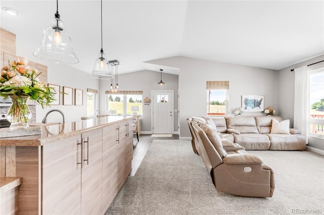 carpeted living room with sink and vaulted ceiling