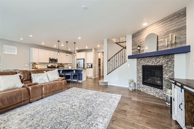 living room featuring sink, a stone fireplace, and dark hardwood / wood-style floors